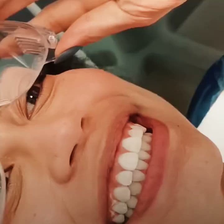Paciente sorrindo durante um atendimento odontológico.
